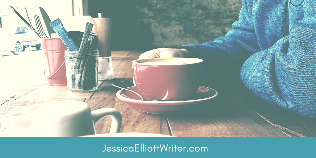 Writer sitting with coffee cup in diner overlooking street. 